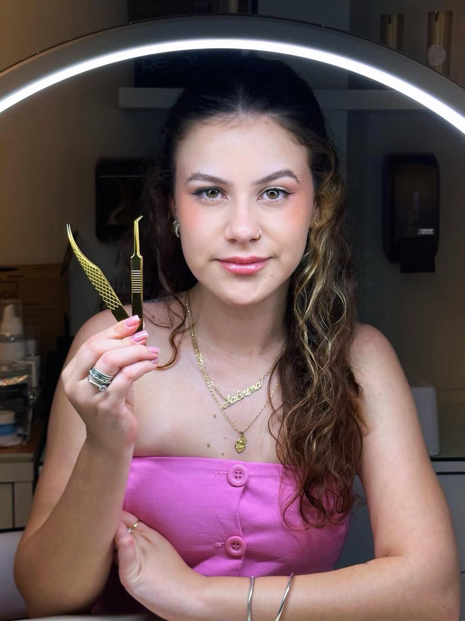 Sabrina Laguna segurando pinças de extensão de cílios em seu studio